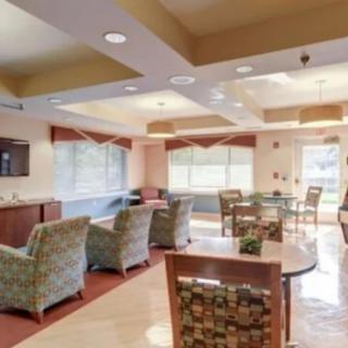 A well-lit lounge with comfortable seating and tables, featuring large windows that allow natural light to enter.