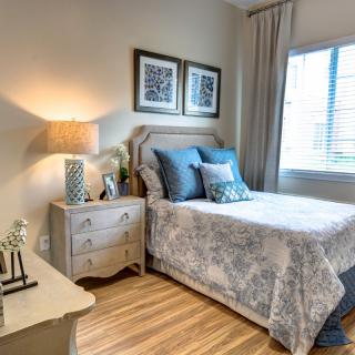 A cozy bedroom with a neatly arranged bed, decorative pillows, and soft lighting from a lamp on the nightstand.