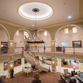 A luxurious hotel lobby featuring a grand staircase and an ornate chandelier.