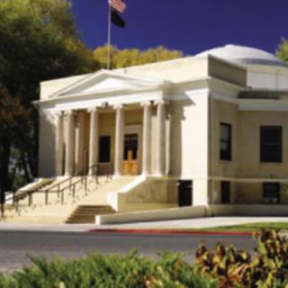 A neoclassical building with columns and a staircase, adorned by an American flag.