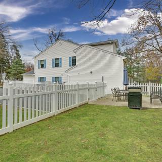 A white house with blue shutters, surrounded by a fenced yard with a patio area.