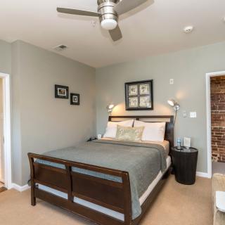 A modern bedroom with a comfortable bed, ceiling fan, and stylish decor.