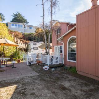 A cozy outdoor patio area with seating, surrounded by trees and a house with large windows.