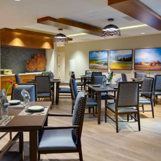 A cozy restaurant dining area with neatly arranged tables and chairs, adorned with artwork on the walls.