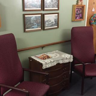 A cozy waiting area with chairs and framed pictures on the wall.