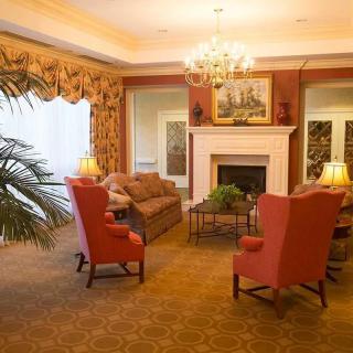 A cozy living room with elegant furnishings, featuring a fireplace and chandelier.