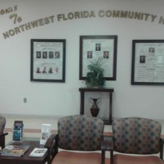 A waiting area in Northwest Florida Community Hospital featuring comfortable chairs and framed photographs.