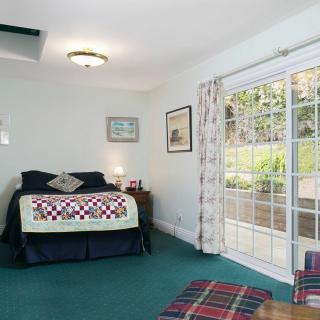 A cozy bedroom with a large bed, colorful quilt, and sliding glass doors leading outside.