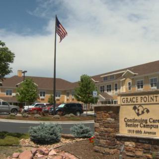 A view of a senior living center with an American flag and a sign in the foreground.