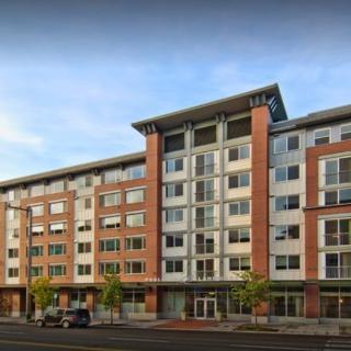 A modern multi-story apartment building with a combination of brick and glass facade.