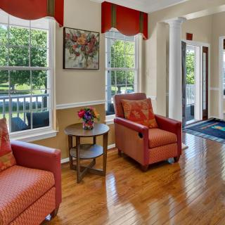 A cozy living room with red armchairs and large windows letting in natural light.