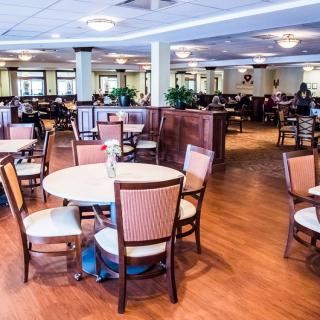 An empty restaurant dining area with neatly arranged tables and chairs on a wooden floor.