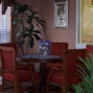 A cozy dining area with a table and four chairs, surrounded by lush plants and decor.