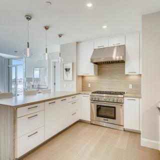 A modern kitchen featuring stainless steel appliances, white cabinets, and a spacious island with pendant lighting.