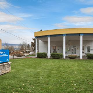 A bank building with a grassy lawn and a sign in the foreground.