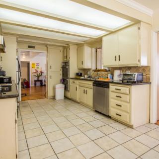 A modern kitchen with tiled flooring, cabinetry, and stainless steel appliances.