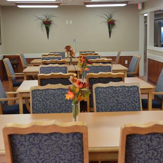 An empty dining area with neatly arranged tables and chairs, adorned with floral centerpieces.