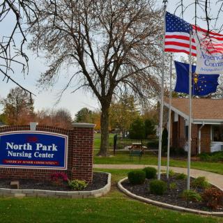 Exterior view of North Park Nursing Center with flags and signage.