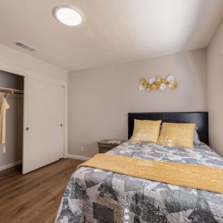 A cozy bedroom with a bed, quilt, pillows, and an open closet.