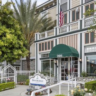 A hotel entrance with green awnings and an American flag displayed.