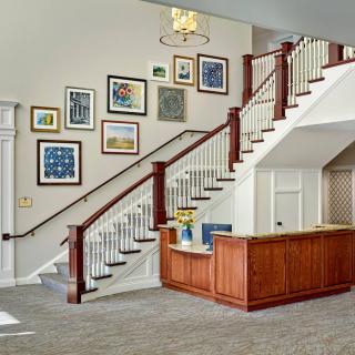 A modern interior featuring a staircase with a gallery wall and a reception desk.