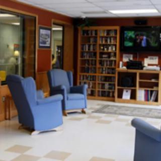 A cozy waiting room with blue chairs, a bookshelf, and a television.