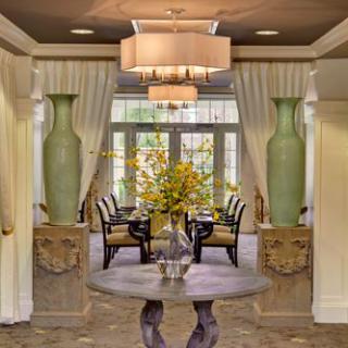 Elegant hallway leading to a dining area, featuring large vases and a central table with floral arrangement.
