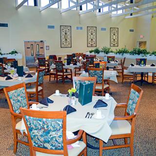 A spacious dining area with neatly arranged tables and chairs, featuring elegant table settings.