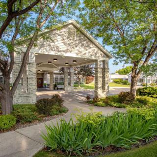 A welcoming building entrance surrounded by lush greenery and a paved pathway.