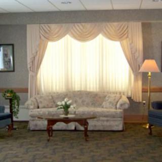 A cozy living room setting with a sofa, armchairs, curtains, and a floor lamp.
