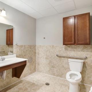 A clean, modern bathroom with a toilet, sink, and wall-mounted cabinet.