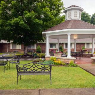 A peaceful garden area with a gazebo and seating surrounded by greenery.