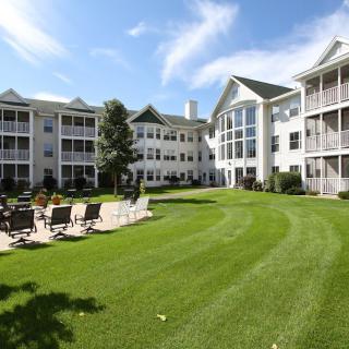 A view of a residential apartment complex with a well-maintained lawn and outdoor seating area.
