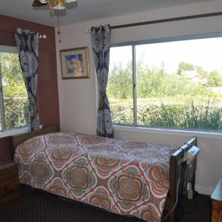 A cozy bedroom with a single bed and large window offering an outside view.