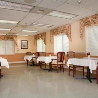 An empty dining room with neatly arranged tables and chairs, featuring elegant curtains and soft lighting.