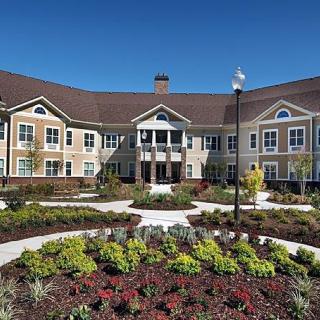 A large, beautifully landscaped residential building under a clear blue sky.