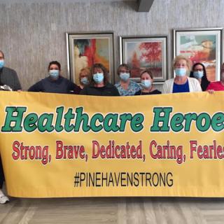 A group of healthcare professionals proudly displaying a banner honoring their dedication and bravery.