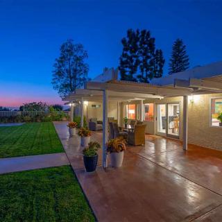 A cozy backyard patio at dusk with outdoor lighting and a landscaped garden.