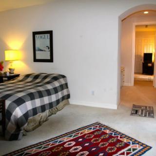 A cozy bedroom interior with a plaid bedspread and colorful rugs.