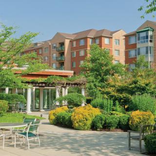 A well-maintained garden and patio area in front of a modern apartment building on a sunny day.