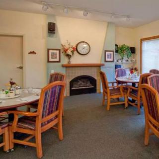 A cozy dining area featuring neatly arranged tables and chairs, with a decorative fireplace and wall accents.