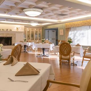 An elegant dining room with neatly arranged tables and chairs, featuring a chandelier and soft lighting.