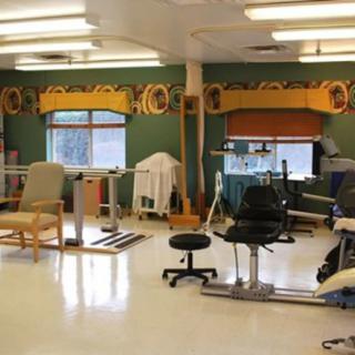 A physical therapy room equipped with various exercise machines and chairs.