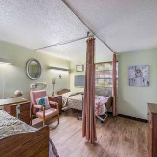 A cozy shared bedroom in a healthcare facility, featuring two beds and comfortable seating.