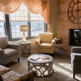 A cozy living room with comfortable seating, a fireplace, and ample natural light streaming in through the windows.