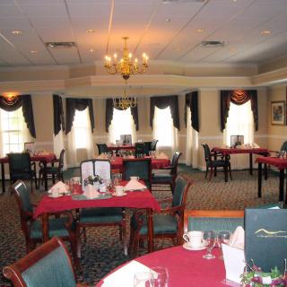 An elegantly set dining room with red tablecloths and neatly arranged furniture.