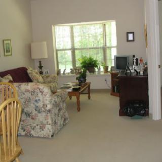 A cozy living room with floral sofa, desk area, and a view of greenery outside.