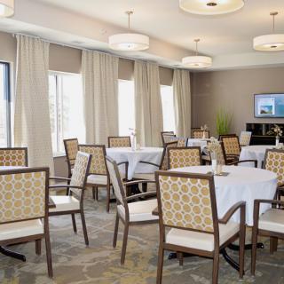 A well-lit dining room with neatly arranged tables and chairs, featuring elegant interior design elements.