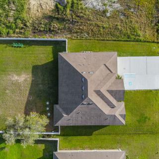 Aerial view of a house with a spacious backyard and driveway.