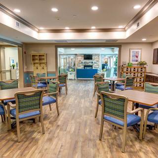 A well-lit dining area with neatly arranged tables and chairs, featuring wooden flooring and a welcoming atmosphere.